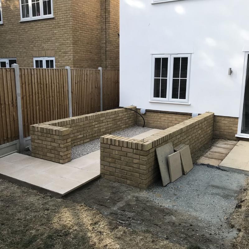 The foundations and dwarf wall. I opted for a central paved path with shingle under each bench for drainage. Electrical sockets were finished by this point, but the black tube supplying water hadn't yet been connected to a tap.